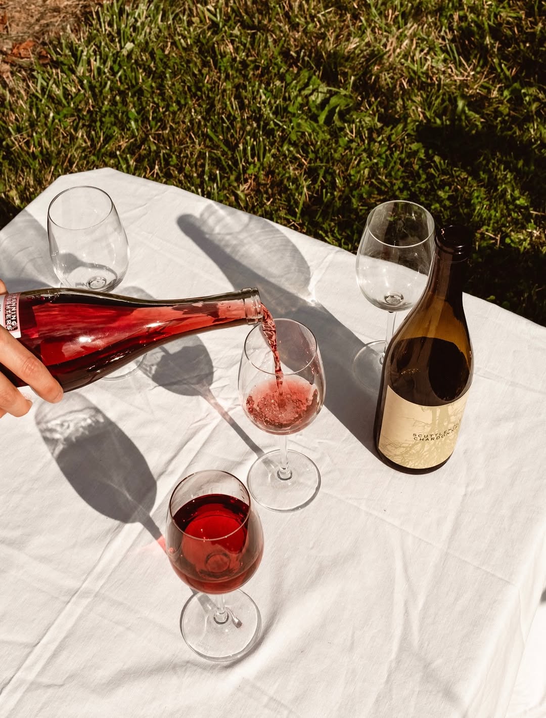 Lagrein Rosato being poured into glasses on a white linen tablecloth in the grass